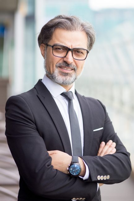 Closeup portrait of serious middle-aged handsome business man looking at camera and standing with his arms crossed